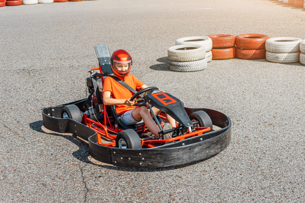 Glücklicher Teenager, der ein Go-Kart-Auto über das Cartodrom fährt. Hobbys und Extremsport für ein Kind und die Erfüllung eines Traums - Foto, Bild