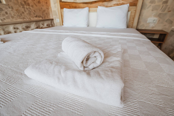 Zbliżenie dwóch ułożonych ręczników na dużym łóżku. Koncepcja zakwaterowania i gościnności - Zdjęcie, obraz