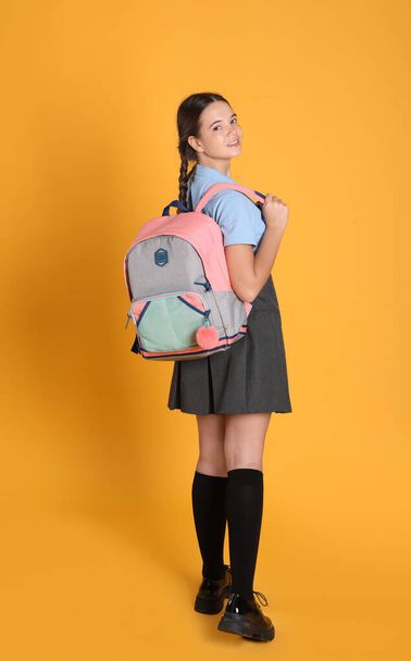 Teenage girl in school uniform with backpack on orange background - Foto, immagini
