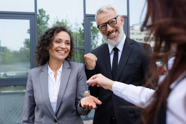 happy african american businesswoman taking key from blurred realtor near excited colleague showing success gesture - Fotoğraf, Görsel