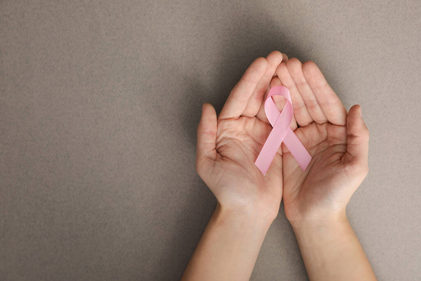 トップ ビュー テキストのためのスペースと、灰色の背景にピンクのリボンを保持している女性。乳房癌意識概念 - 写真・画像