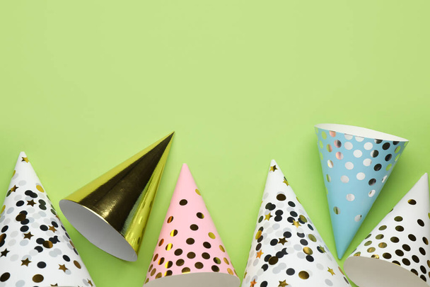 Bright party hats on light green background, flat lay. Space for text - Foto, imagen