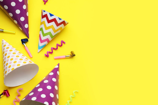 Bright party hats, streamers and horns on yellow background, flat lay. Space for text - Photo, Image