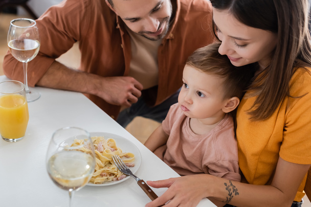 Parents looking at son near pasta and drinks at home  - Photo, image