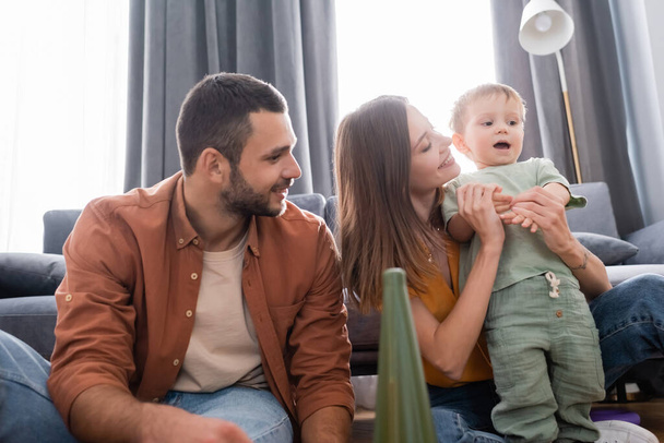 Parents sitting near toddler son in living room  - Photo, Image