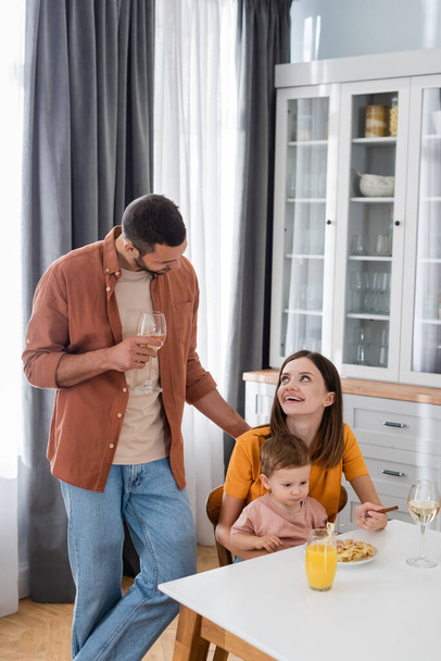 Man holding wine near wife and son during dinner at home  - Photo, image
