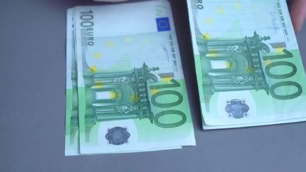 Close-up van een onherkenbare zakenvrouw die Europees geld telt op een grijze achtergrond. Bankbiljetten in coupures van vijftig en honderd euro. - Video