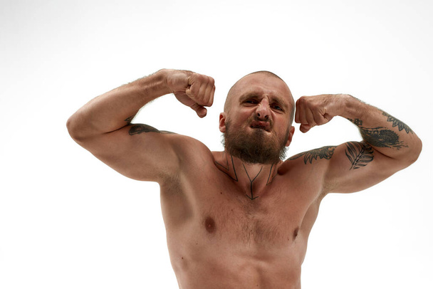 Young aggressive caucasian man show biceps muscles - Фото, изображение