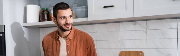 Χαμογελώντας άντρας κοιτάζοντας μακριά στην κουζίνα, πανό  - Φωτογραφία, εικόνα