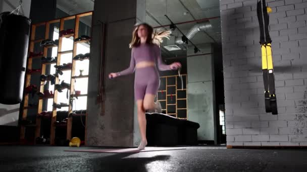 Mujer joven saltando sobre la cuerda saltando en el gimnasio - Metraje, vídeo