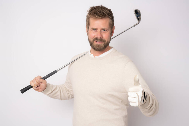 Young handsome man playing golf with thumb up standing isolated over white background. - 写真・画像