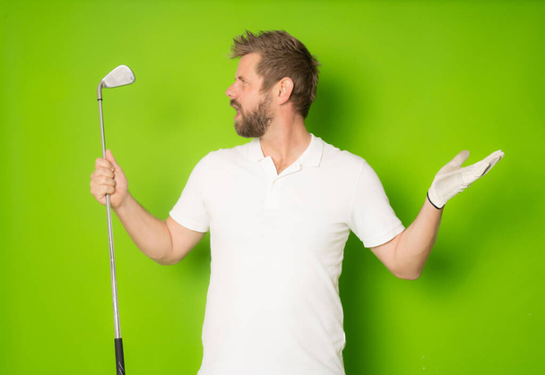 Bonito jovem vestindo camiseta branca jogando golfe sobre fundo verde isolado. - Foto, Imagem
