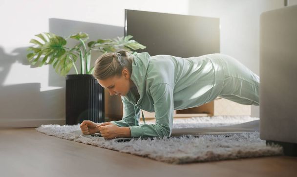 Mujer haciendo ejercicio de tablón. Concepto de entrenamiento físico en casa. - Foto, imagen
