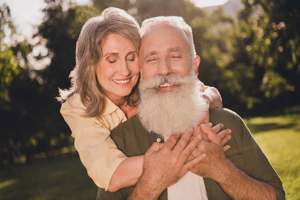 Photo of positive grey haired happy people couple embrace spring holiday vacation outside outdoors in park - Φωτογραφία, εικόνα