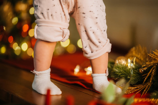 Cute little baby legs in room with Christmas tree - Фото, изображение