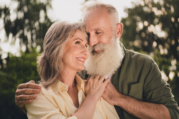 Photo of optimistic elder couple hug look wear shirt walk in park outside outdoors - Фото, изображение