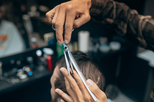 Веселый молодой бородатый мужчина стрижется в парикмахерской - Фото, изображение