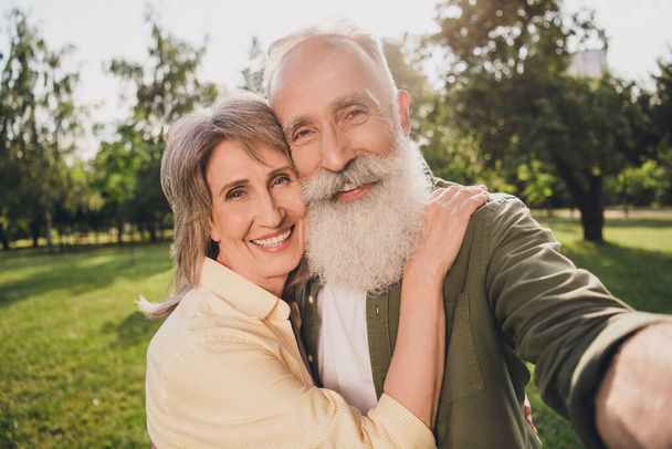 Photo of funny elder white hair couple do selfie wear casual shirts outdoors rest in park - Фото, изображение
