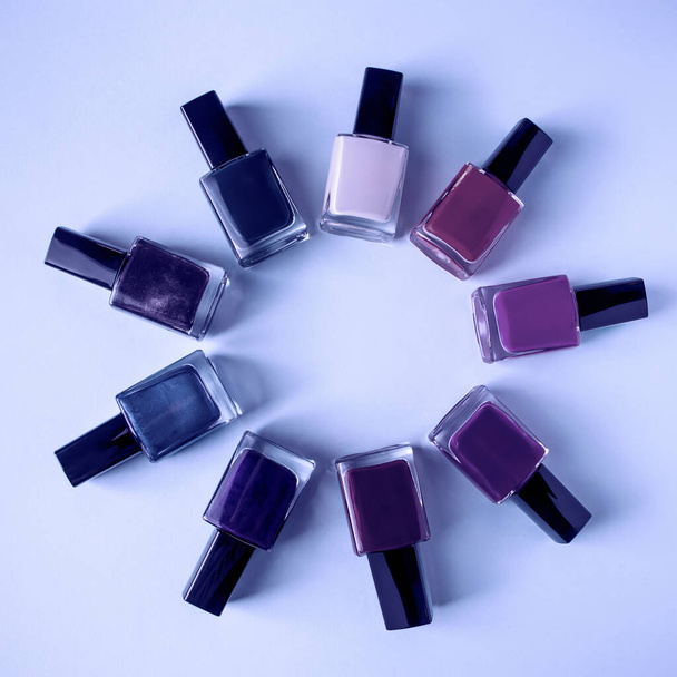 Group of bright colored nail polishes on a purple background. Set of decorative cosmetics for body care. Trendy color of the year 2022. - Photo, Image