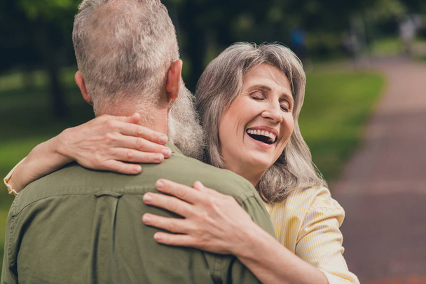 Back photo of laugh aged couple hug wear shirt walk in park outside outdoors - Фото, изображение