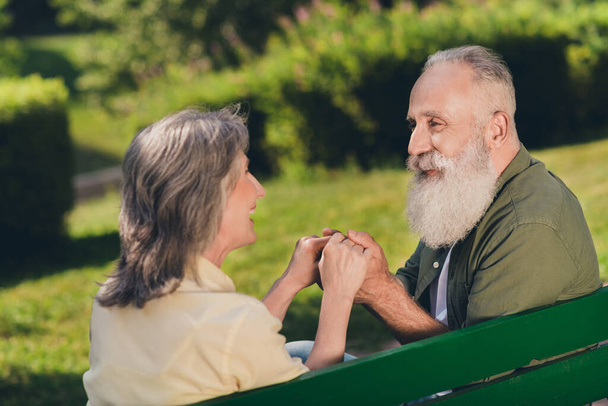 Zdjęcie szczęśliwych pozytywnych starych emerytów kobieta mężczyzna siedzieć ławka trzymać za ręce natura zielony zewnątrz w miejskim parku - Zdjęcie, obraz