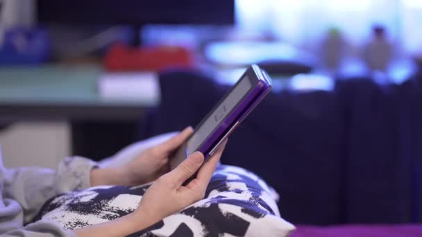 Junge schöne Kaukasierin sitzt zu Hause mit E-Book-Reader im Bett - Filmmaterial, Video
