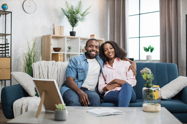 Happy african couple sitting on couch in embrace - Photo, Image