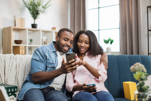 Loving couple sitting on couch and using smartphones - Foto, afbeelding
