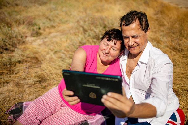 Senior feliz pareja se divierten usando tableta digital PC en la playa durante el momento de relax - Concepto de jubilados activos y estilo de vida de viaje - Interacción con las nuevas tendencias y tecnologías informáticas - Foto, Imagen