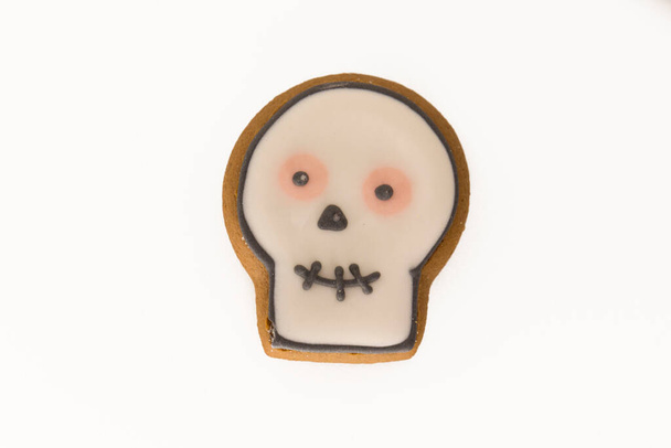Halloween gingerbread cookie with icing in shape of a skull. Isolated close up top view shot on a white background - Photo, image