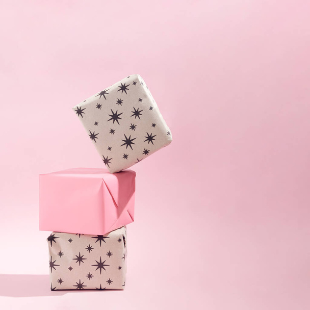 gift boxes with stars.one on the top going to fall.Christmas present concept idea.soft pink background with shadow.Holiday design - Photo, Image