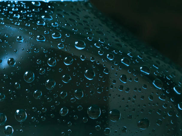 Wasser tropft auf eine Glasflasche. Nahaufnahme der Tröpfchen auf einer dunklen Oberfläche. Selektiver Fokus - Foto, Bild