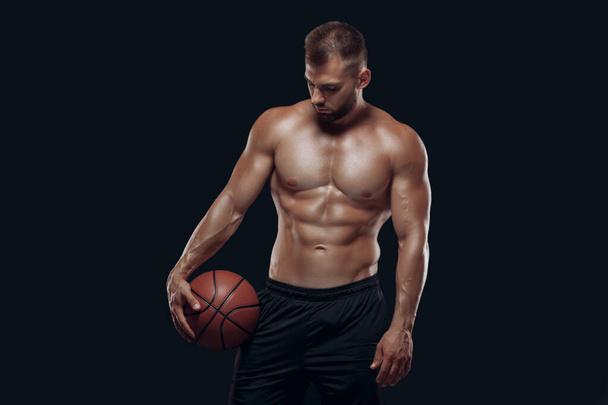 Portrait of a very muscular naked man playing basketball isolated on black background - Fotoğraf, Görsel