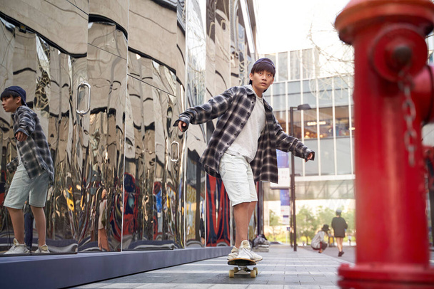 έφηβος ασιατικό παιδί skateboarding σε εξωτερικούς χώρους στο δρόμο - Φωτογραφία, εικόνα