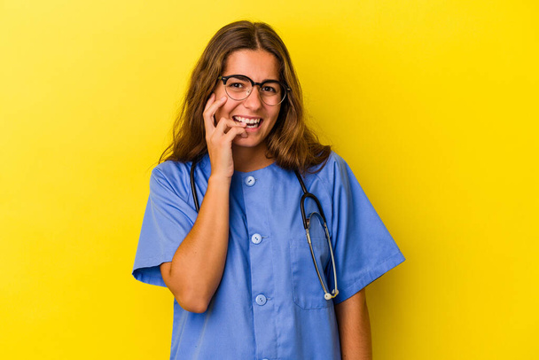 若い看護師の女性は、爪をかむ黄色の背景に隔離,神経と非常に不安. - 写真・画像