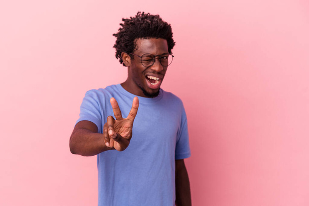 Fiatal afro-amerikai férfi elszigetelt rózsaszín háttér mutatja a második számú ujjak. - Fotó, kép