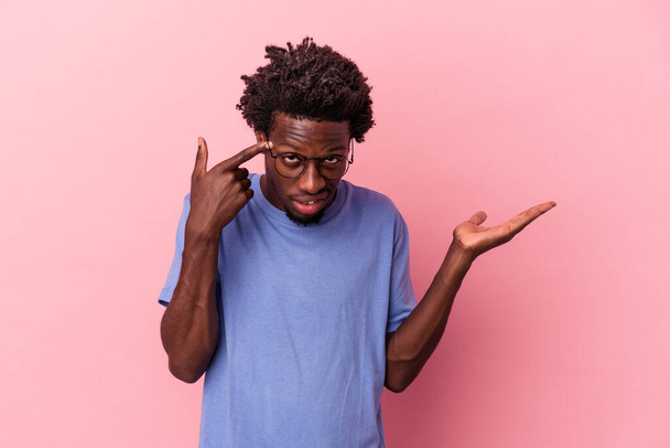 Joven afroamericano aislado sobre fondo rosa mostrando un gesto decepcionante con dedo índice. - Foto, Imagen