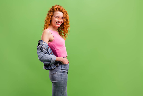 Photo of shiny confident young lady dressed denim clothes glasses smiling arms pocket empty space isolated green color background - Zdjęcie, obraz