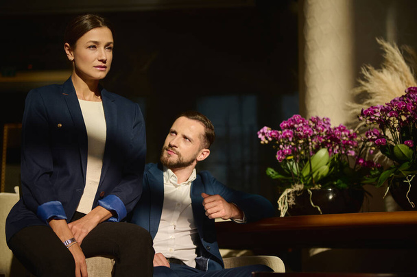 Portrait of two confident people, colleagues on business trip, Caucasian woman and man , business partners sitting on armchair in the lounge zone of a luxury hotel - Φωτογραφία, εικόνα