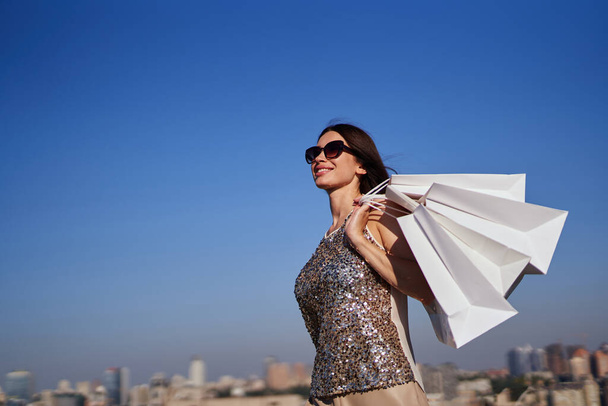 Donna in stile moda con borse della spesa su sfondo urbano - Foto, immagini