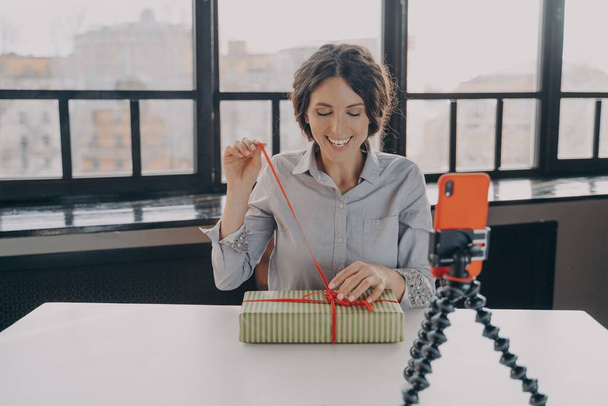 Радісна іспаномовна жінка-блогер відкриває подарункову коробку для запису відео про різдвяний подарунок для свого блогу
 - Фото, зображення