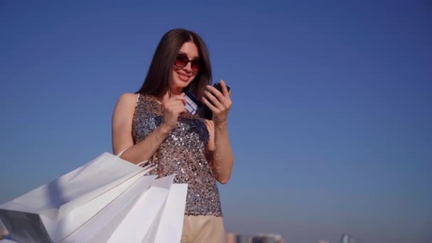 Chica haciendo compras en línea celebración de tarjeta de crédito y teléfono - Metraje, vídeo
