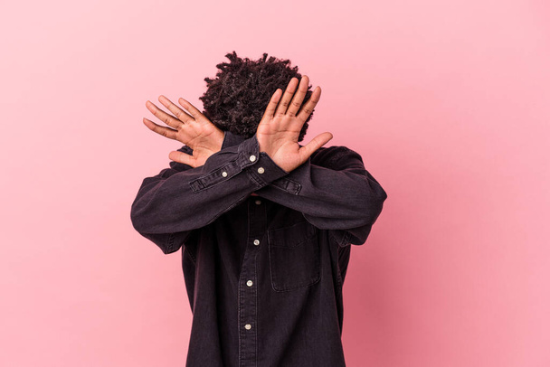 Jovem afro-americano isolado sobre fundo rosa mantendo dois braços cruzados, conceito de negação. - Foto, Imagem