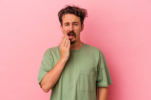 Молодий білий чоловік ізольований на рожевому тлі позіхання показує втомлений жест, що покриває рот рукою
. - Фото, зображення