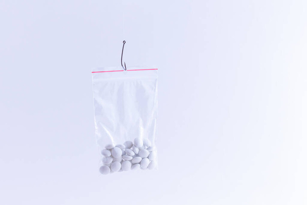 White Pills or Tablets Hanging in Small Ziplock Bag on a Fishing Hook - Photo, image