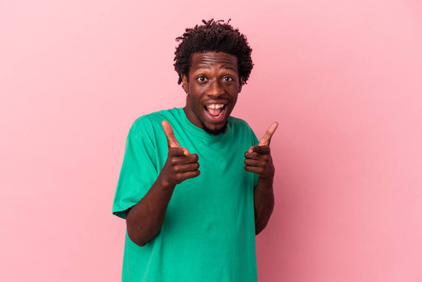 Young african american man isolated on pink background pointing to front with fingers. - 写真・画像