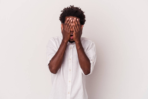 Joven afroamericano aislado sobre fondo blanco divertirse cubriendo la mitad de la cara con la palma. - Foto, Imagen
