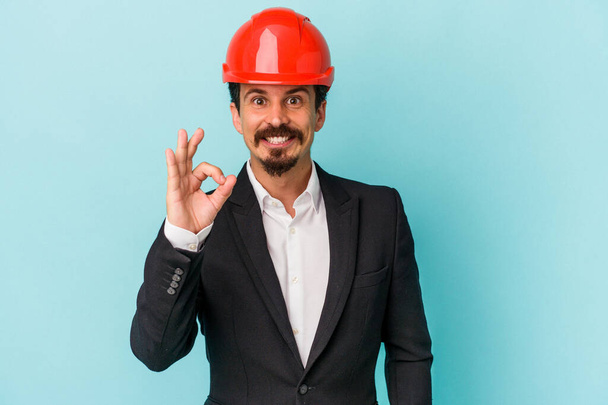 Young architect caucasian man isolated on blue background cheerful and confident showing ok gesture. - Φωτογραφία, εικόνα