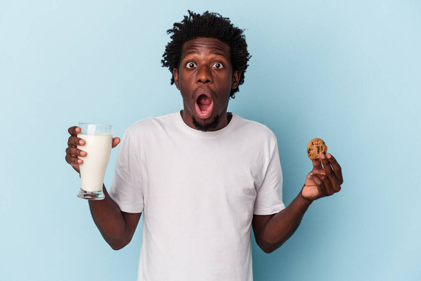Nuori afrikkalainen amerikkalainen mies syö suklaakeksejä ja juo maitoa sinisellä - Valokuva, kuva