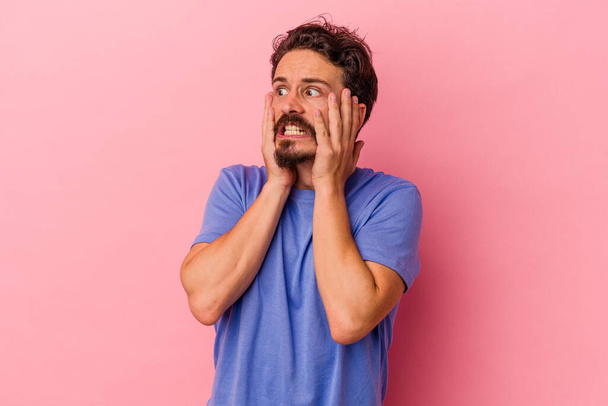 Young caucasian man isolated on pink background scared and afraid. - Photo, Image